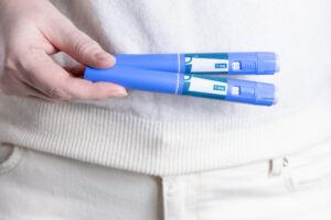 Hand hält Abnehmspritze Ozempic Pen, Klicken mit der Abnehmspritze